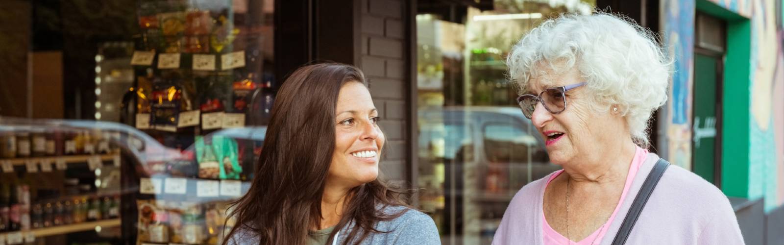 An older woman and younger woman walking arm in arm in a supermarket