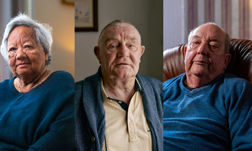 An older woman and two older men look sadly at the camera