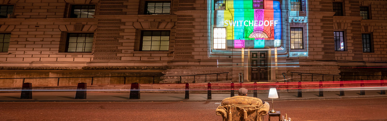 A man watched as a TV is projected onto a building