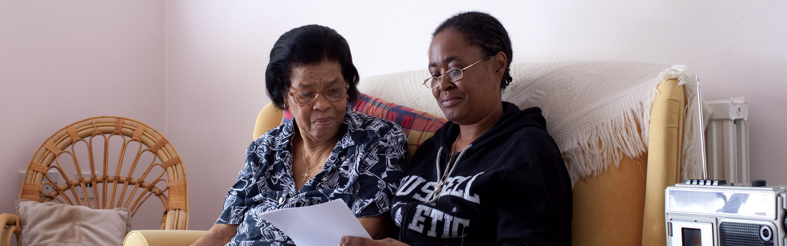 A younger woman and an older woman read together on a sofa