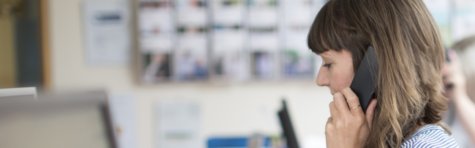 A woman with glasses on an call, in front of a computer screen