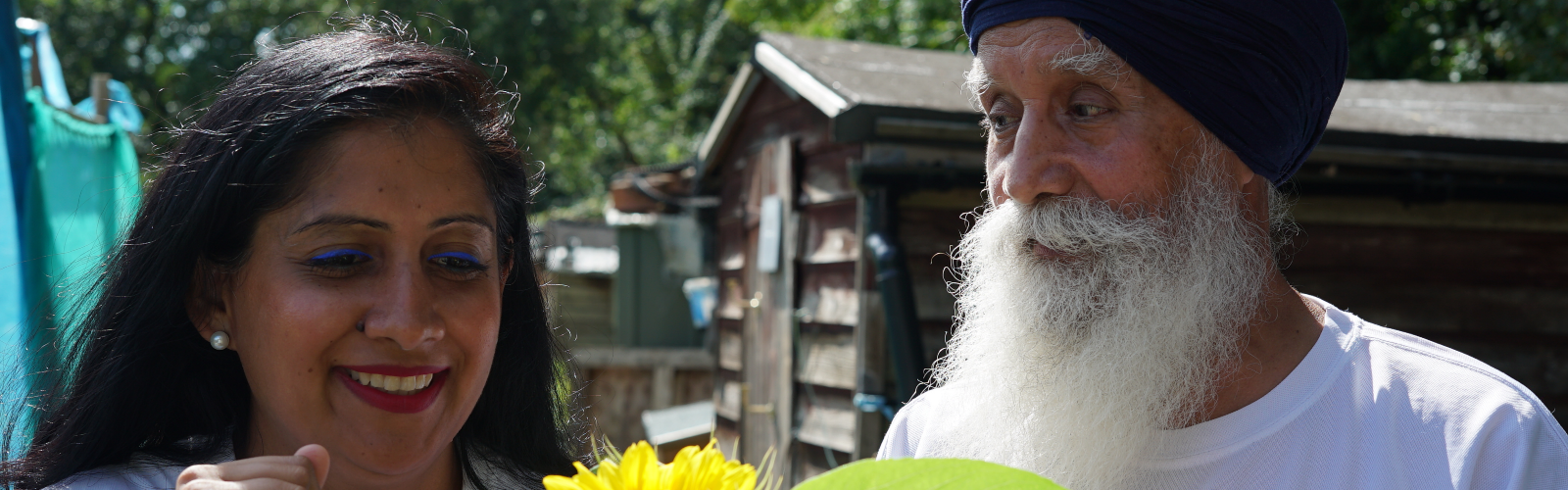 Man with grey beard and wearing a turban smiles at his adult daughter.