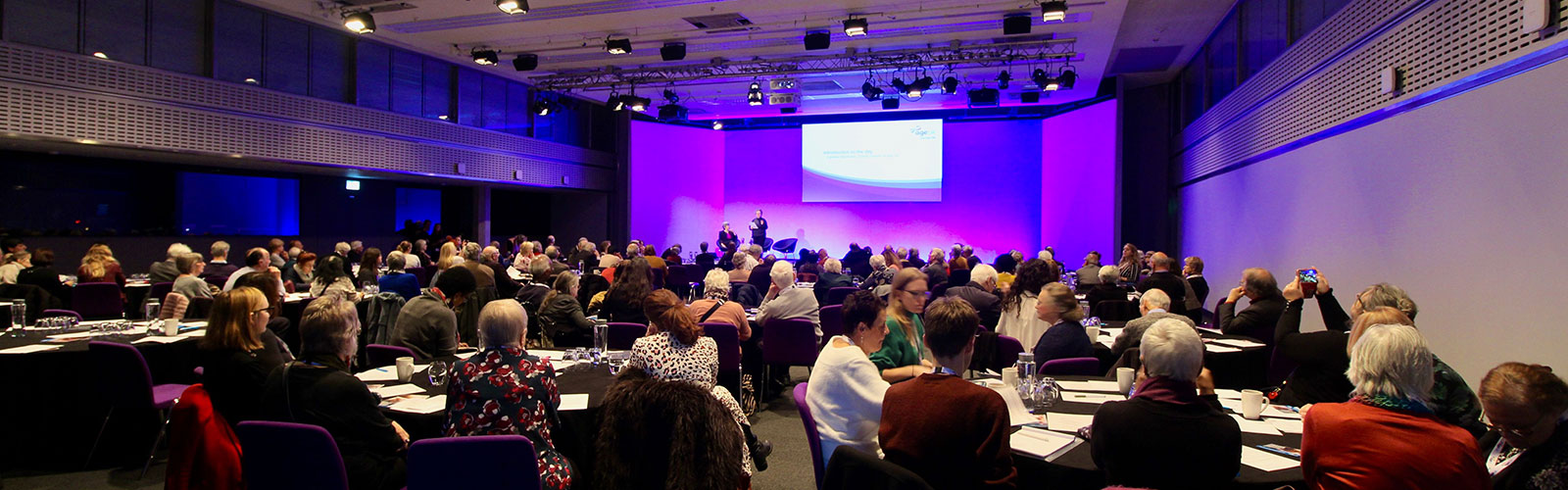 People sitting around tables at Age UK rally