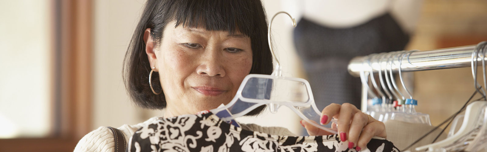 A woman looking at a garment on a clothing hanger