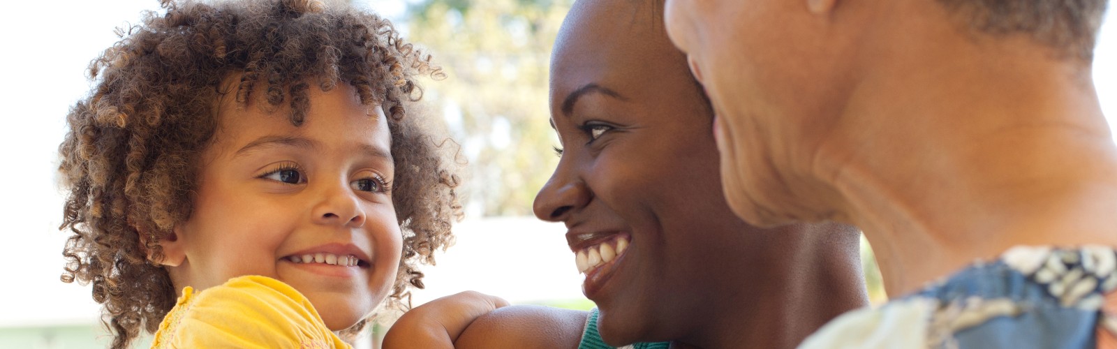 A child, mother and grandmother smile at each other