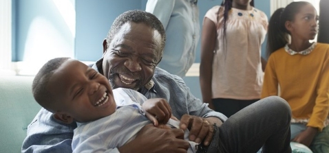 00273 - Laughing grandfather embracing grandson on a sofa while family looks on - 5_3 (1).jpg