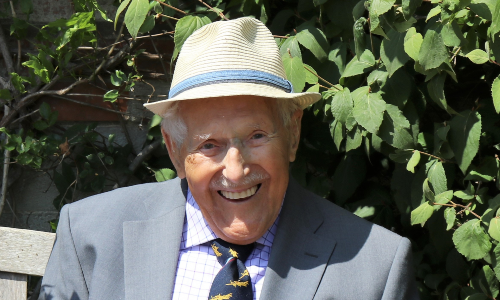 An older man in s straw hat, sat on a bench