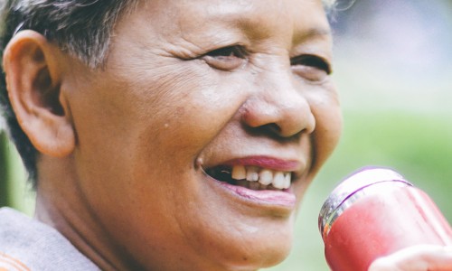 An older women, drinking from a flask