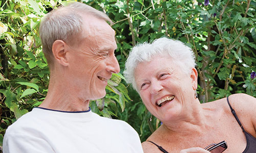 An older man and older woman sat outside, laughing together