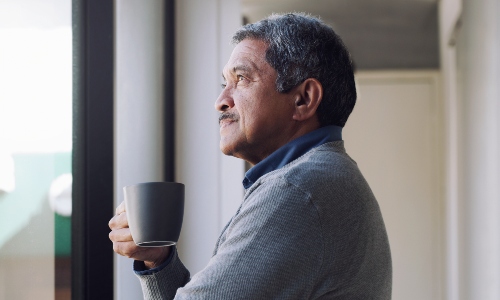 An older man staring out of the window contemplatively