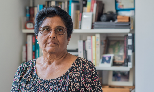 Woman standing in front of bookshelf looking to camera