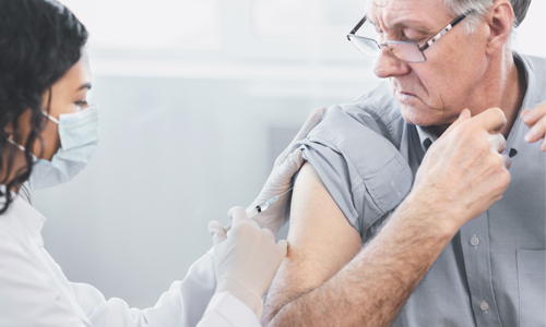 A doctor gives an injection to an older man.