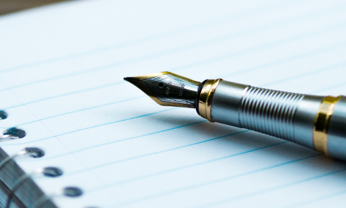 An ink pen resting on a notepad