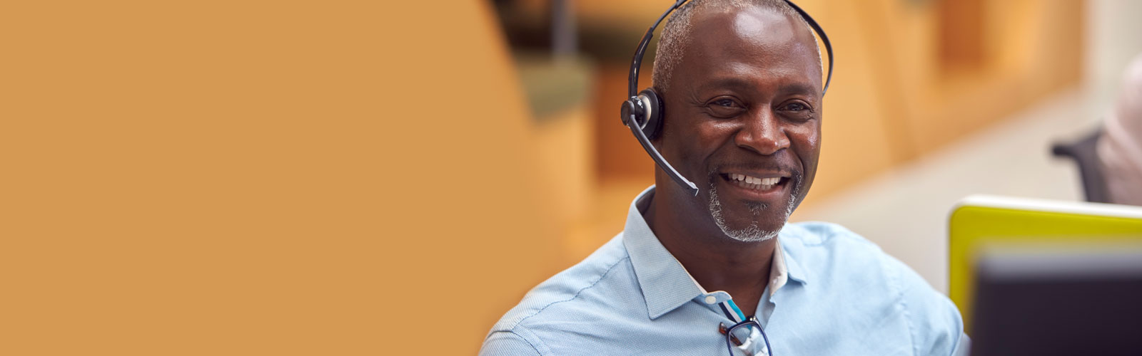 A man in a blue shirt and headset smiling